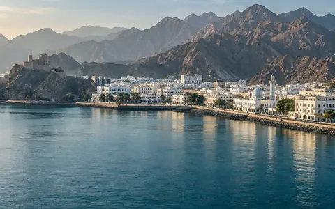 Muscat corniche with a hilltop fort and mountains behind